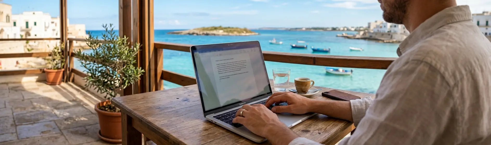 Person working on a laptop at an outdoor terrace with a sea view